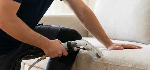 Professional upholstery cleaner deep-cleaning a fabric sofa with a handheld extraction tool, Tempe, AZ.